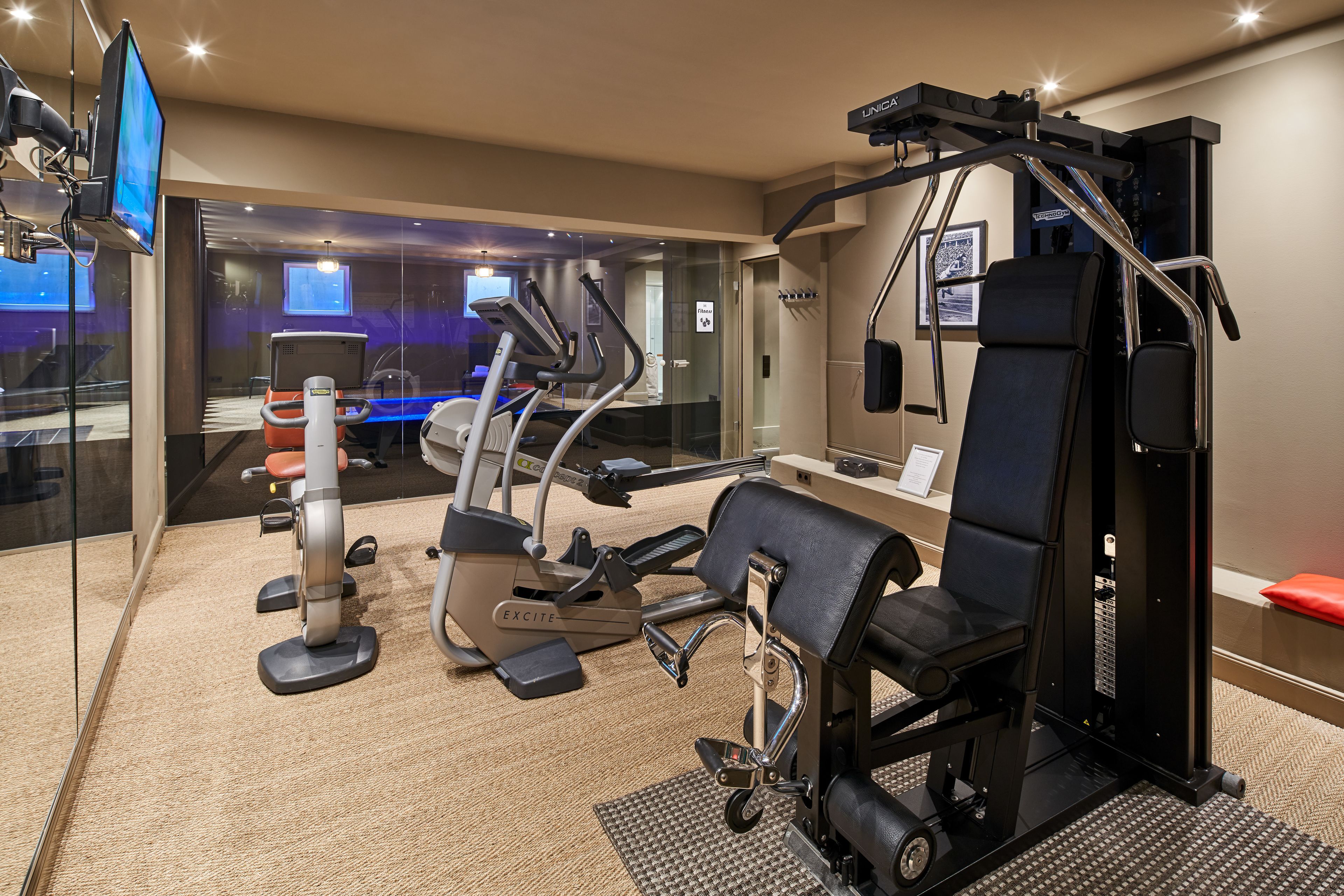A modern gym with various exercise equipment, including a treadmill, elliptical, and weight machines.