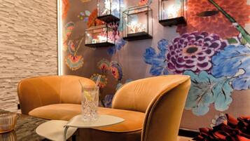 A modern interior with a brick wall, two leather chairs, a small table, and a floral mural.