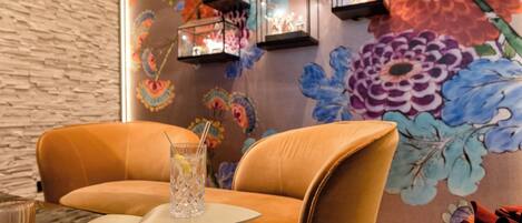 Un interior moderno con pared de ladrillo, dos sillones de cuero, una mesita y un mural floral.