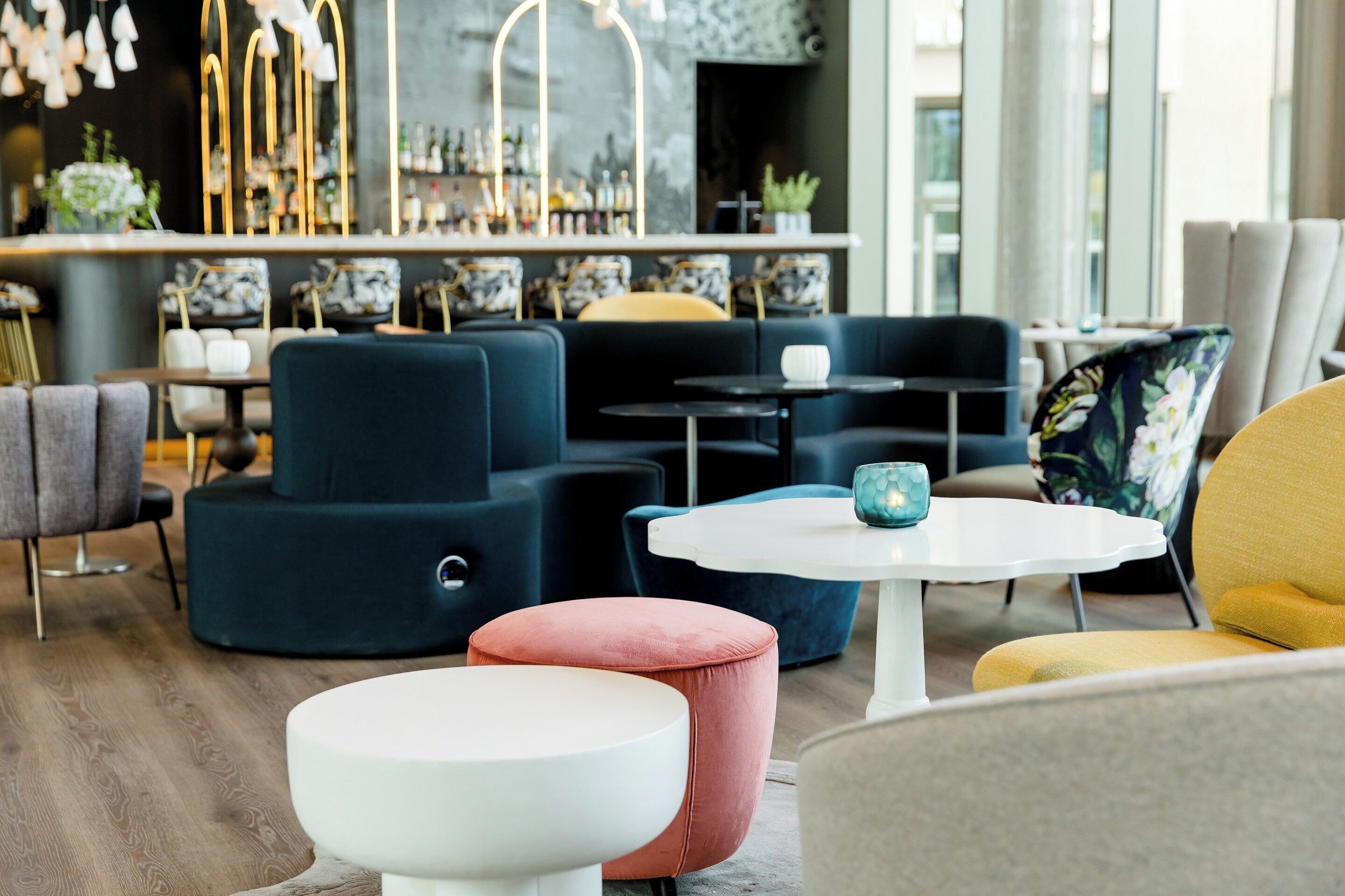 Un espace de détente moderne avec des canapés, une table ronde et un bar en arrière-plan.