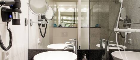 A modern bathroom with a large white sink, two mirrors, a hairdryer, and a shower area.