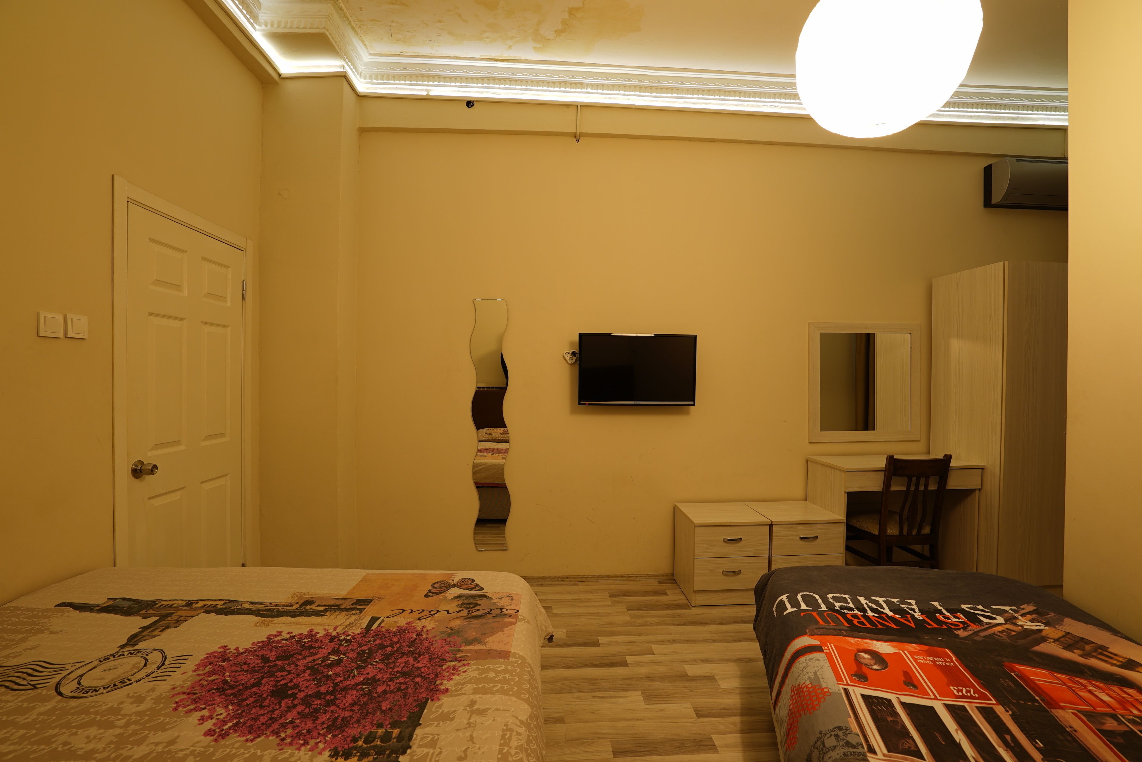A bedroom with a bed, a desk, a chair, a TV, and a wardrobe.