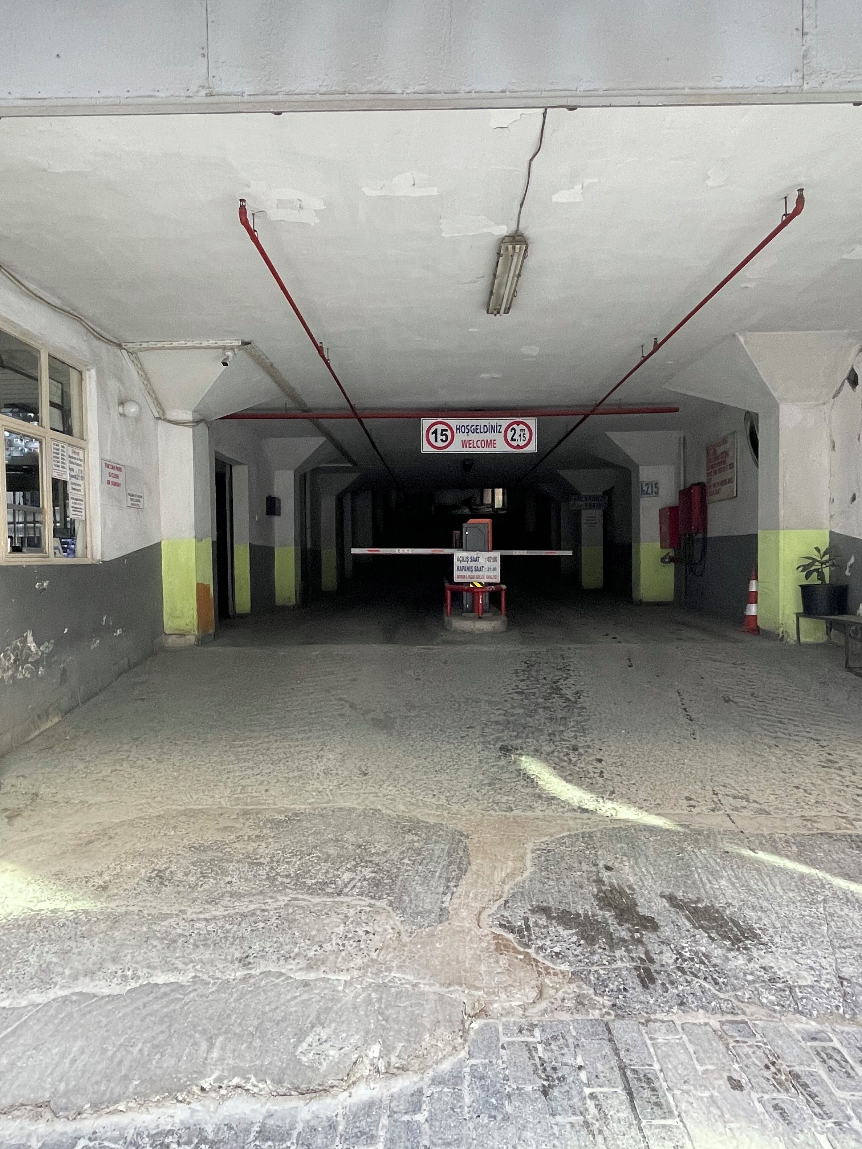 A spacious, dimly lit parking garage with a concrete floor and a central walkway. A sign indicates a 15-minute parking limit.