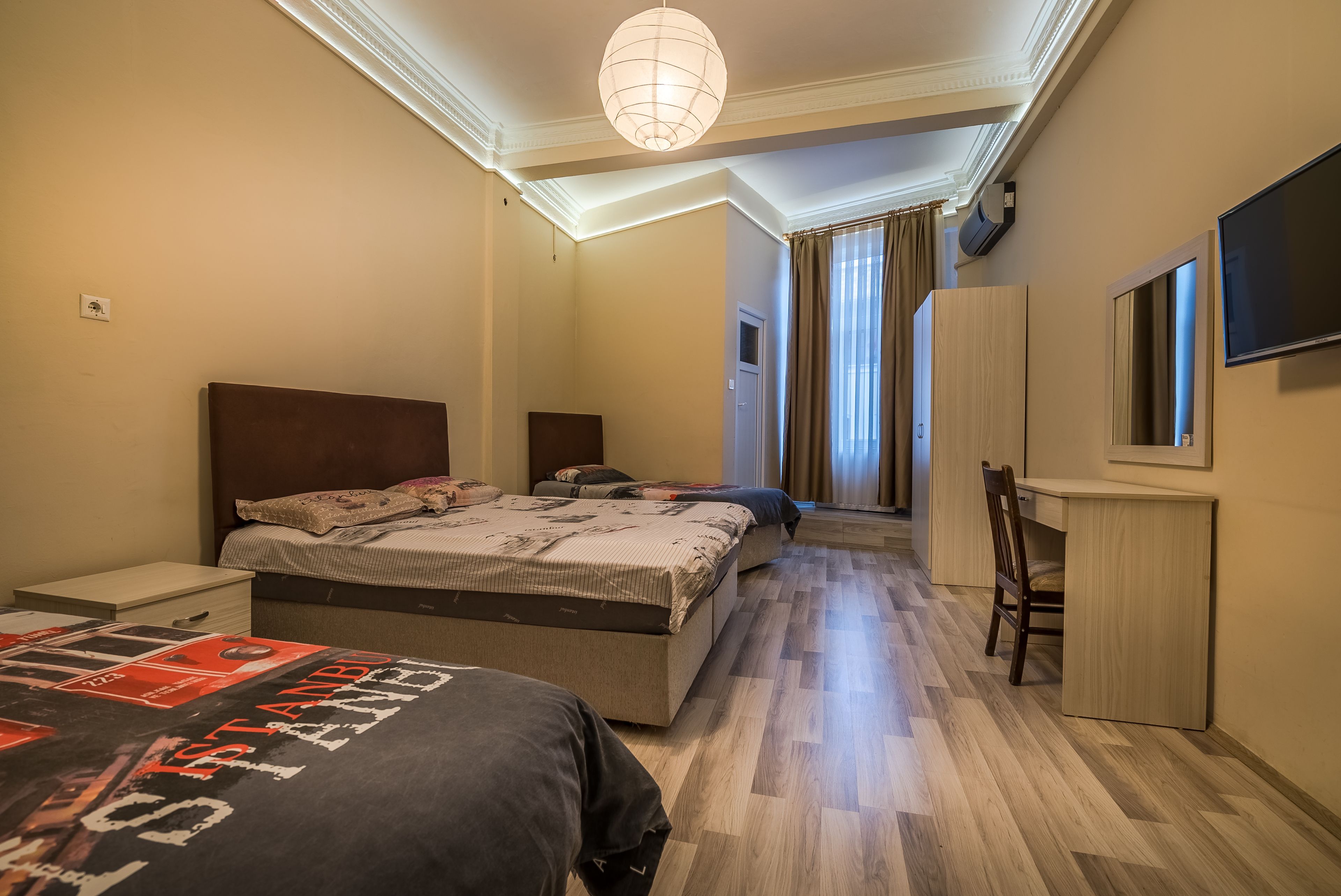 A hotel room with a large bed, a desk, a chair, and a television.