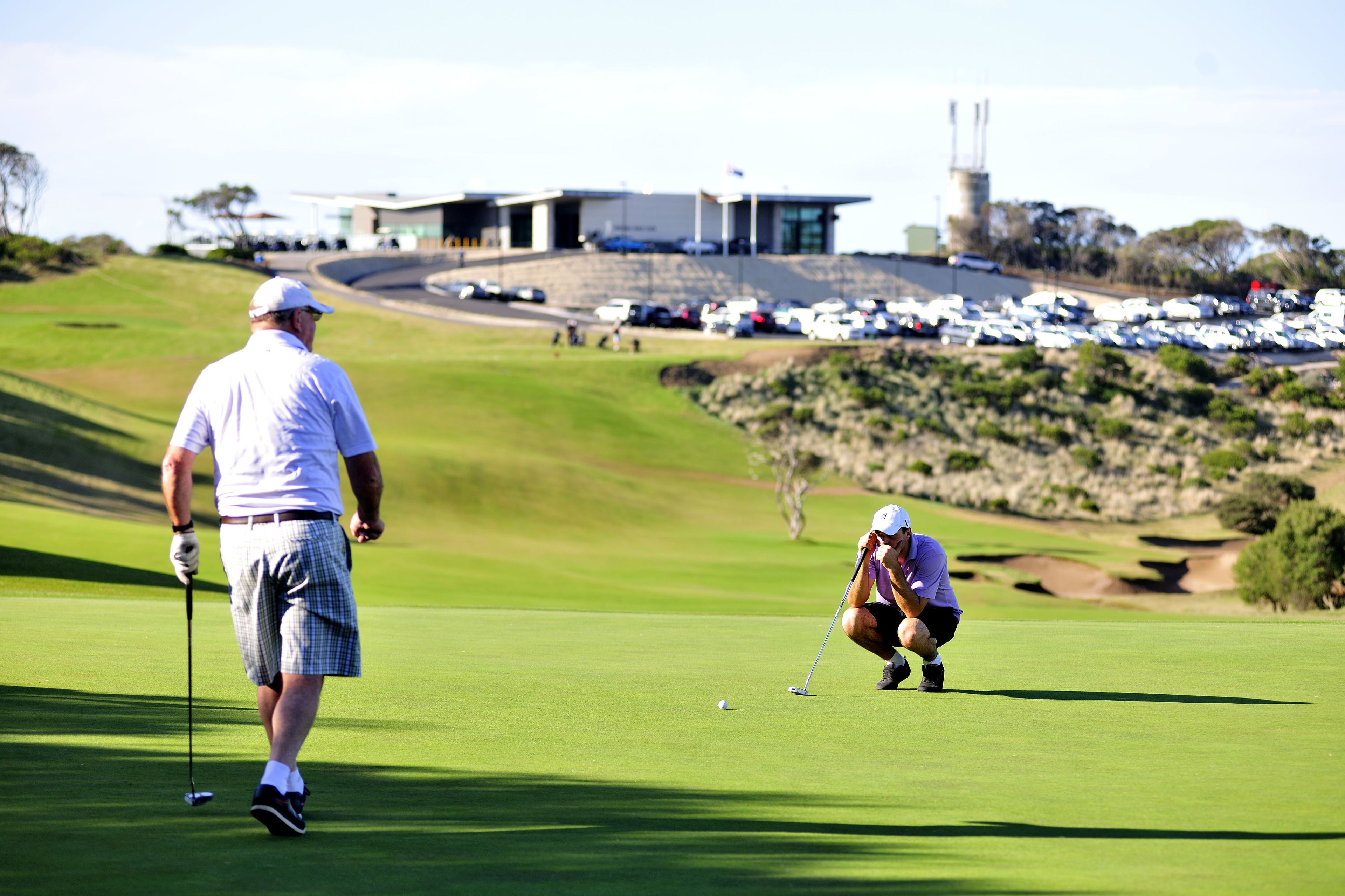 Un campo de golf con un edificio moderno al fondo.