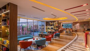 Un espace de détente moderne avec une bibliothèque en bois, un canapé bleu, des fauteuils rouges et une table basse.