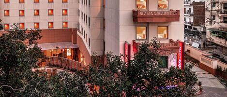 Un hotel con varios pisos, balcones y una entrada bien iluminada.