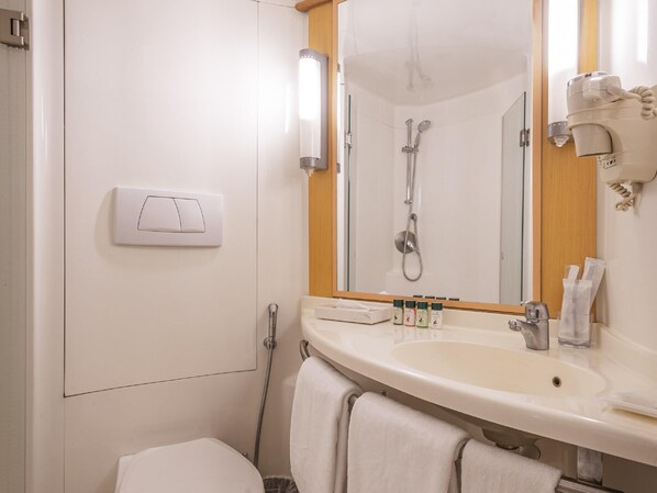 A bathroom with a sink, mirror, shower, and towel rack.