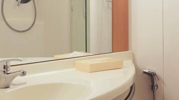 A bathroom with a sink, mirror, towel, and shower.