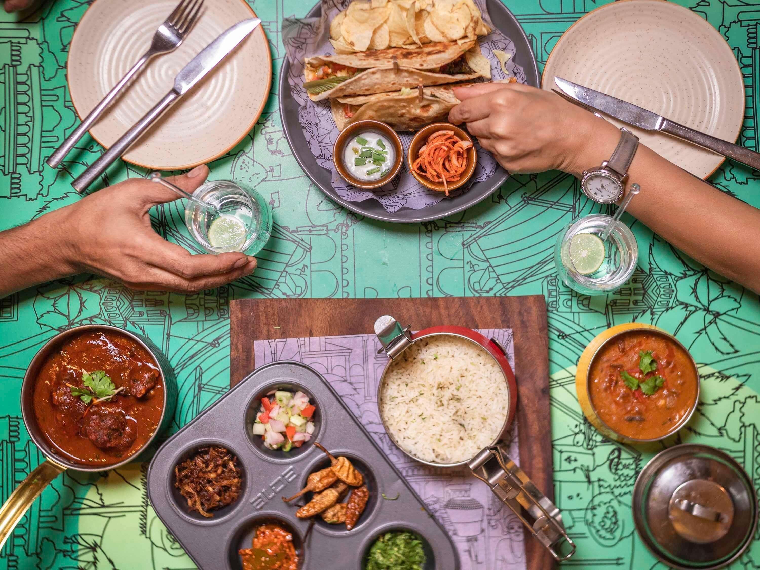Una mesa de comedor con diversos platos, cubiertos y un mantel estampado.