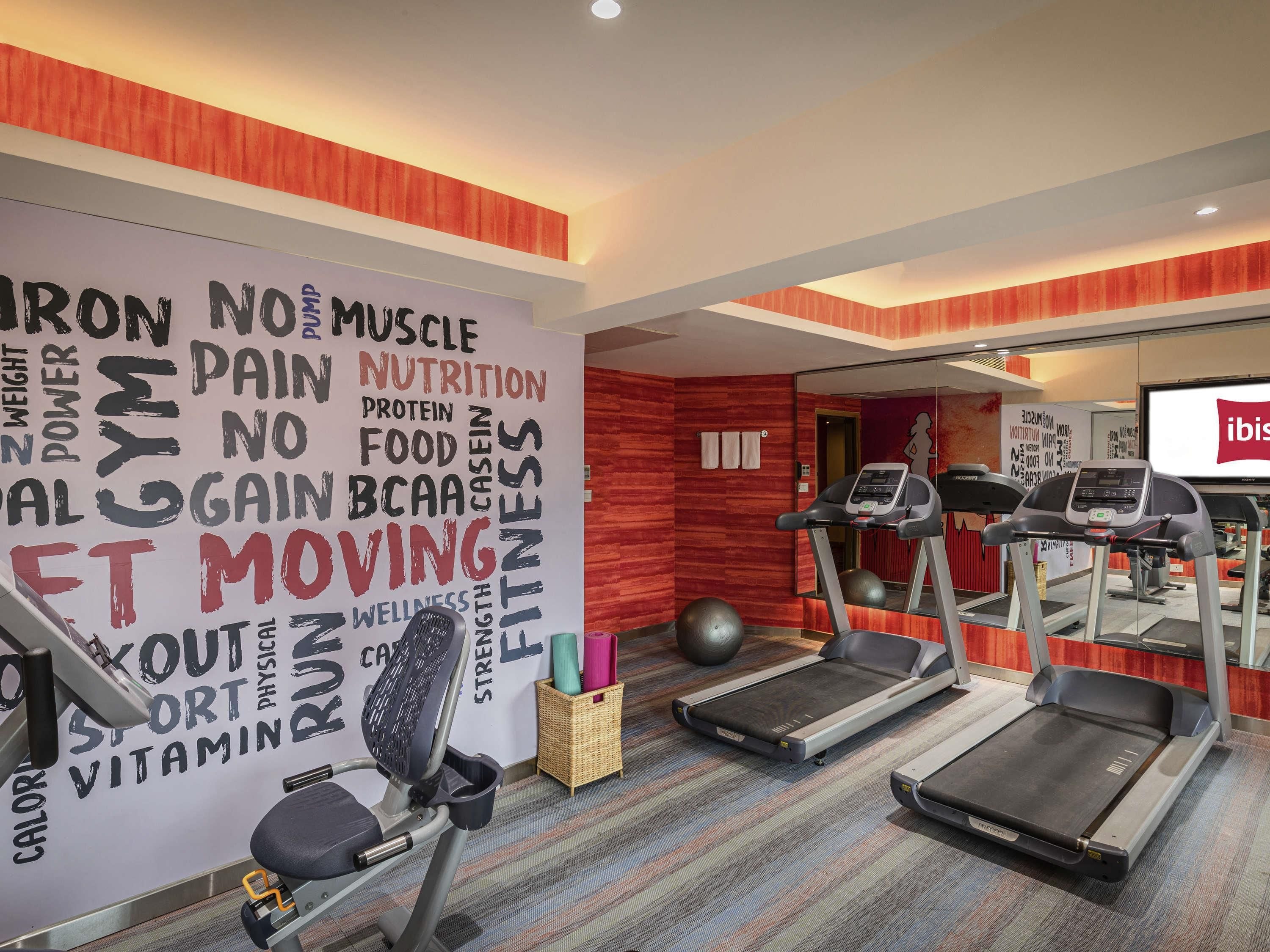 A gym with treadmills, exercise balls, and a wall with fitness-related words.