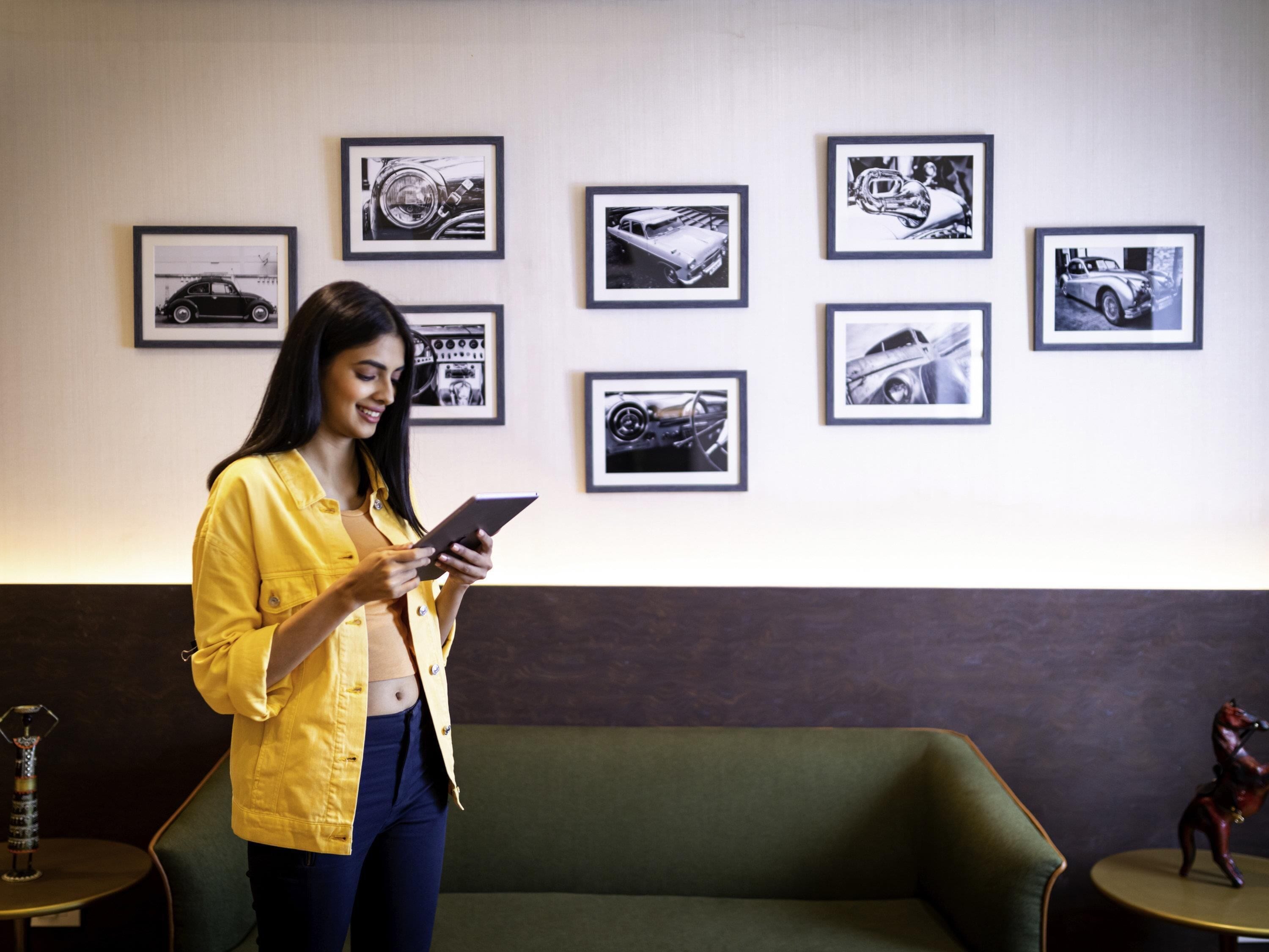 A person standing in a room with a green sofa, a table with a decorative item, and several framed car pictures on the wall.