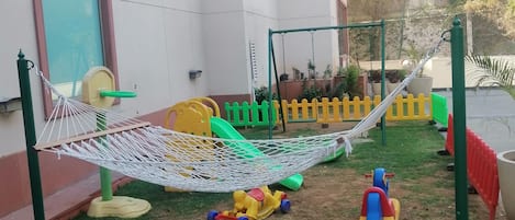 Un espace de jeux pour enfants avec un hamac, des structures de jeu et des jouets.