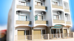 Un hotel de varios pisos con balcones, unidades de aire acondicionado y un cartel que indica que es el Hotel Rebihoz.