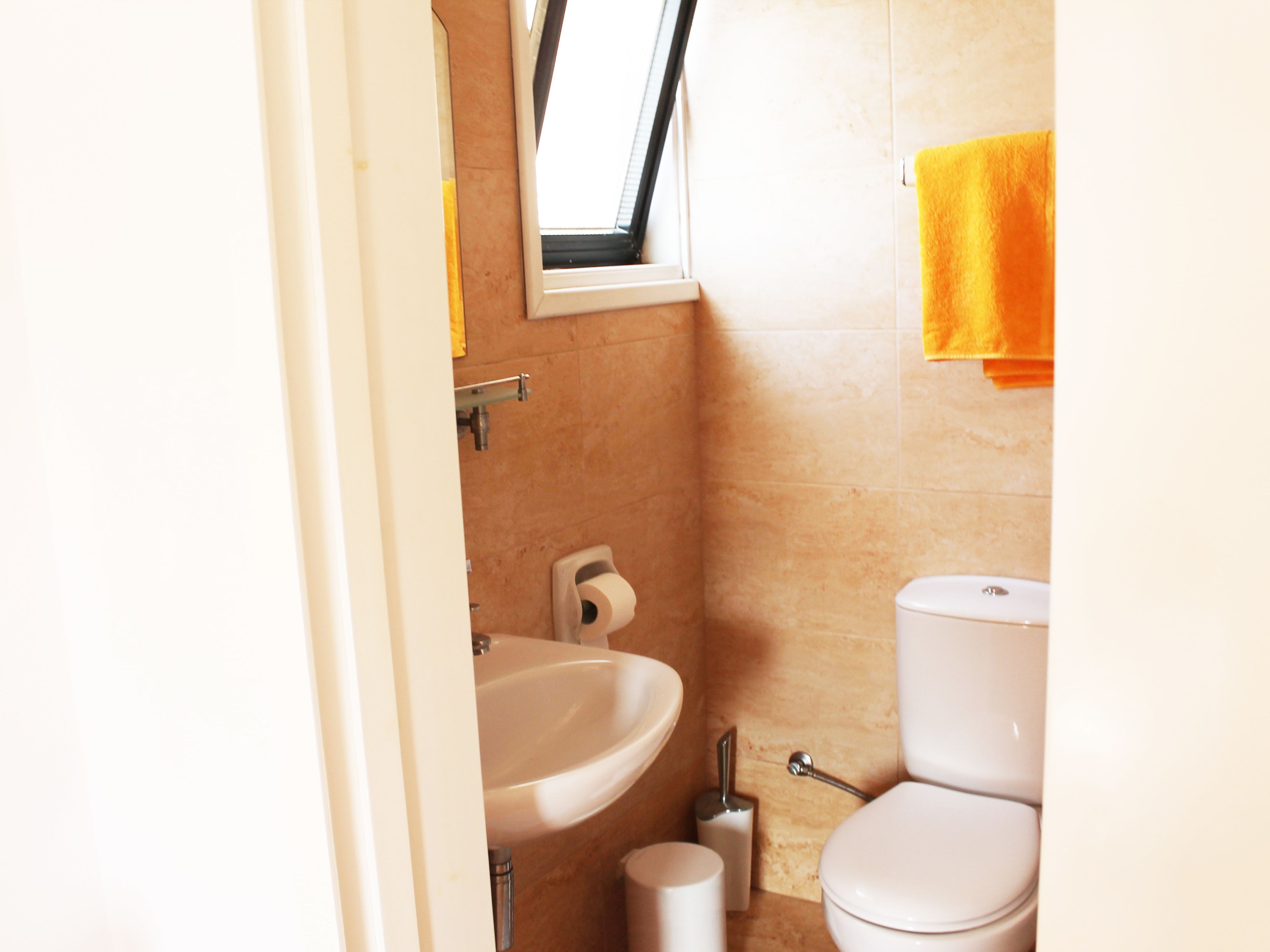A bathroom with a sink, toilet, and a window.