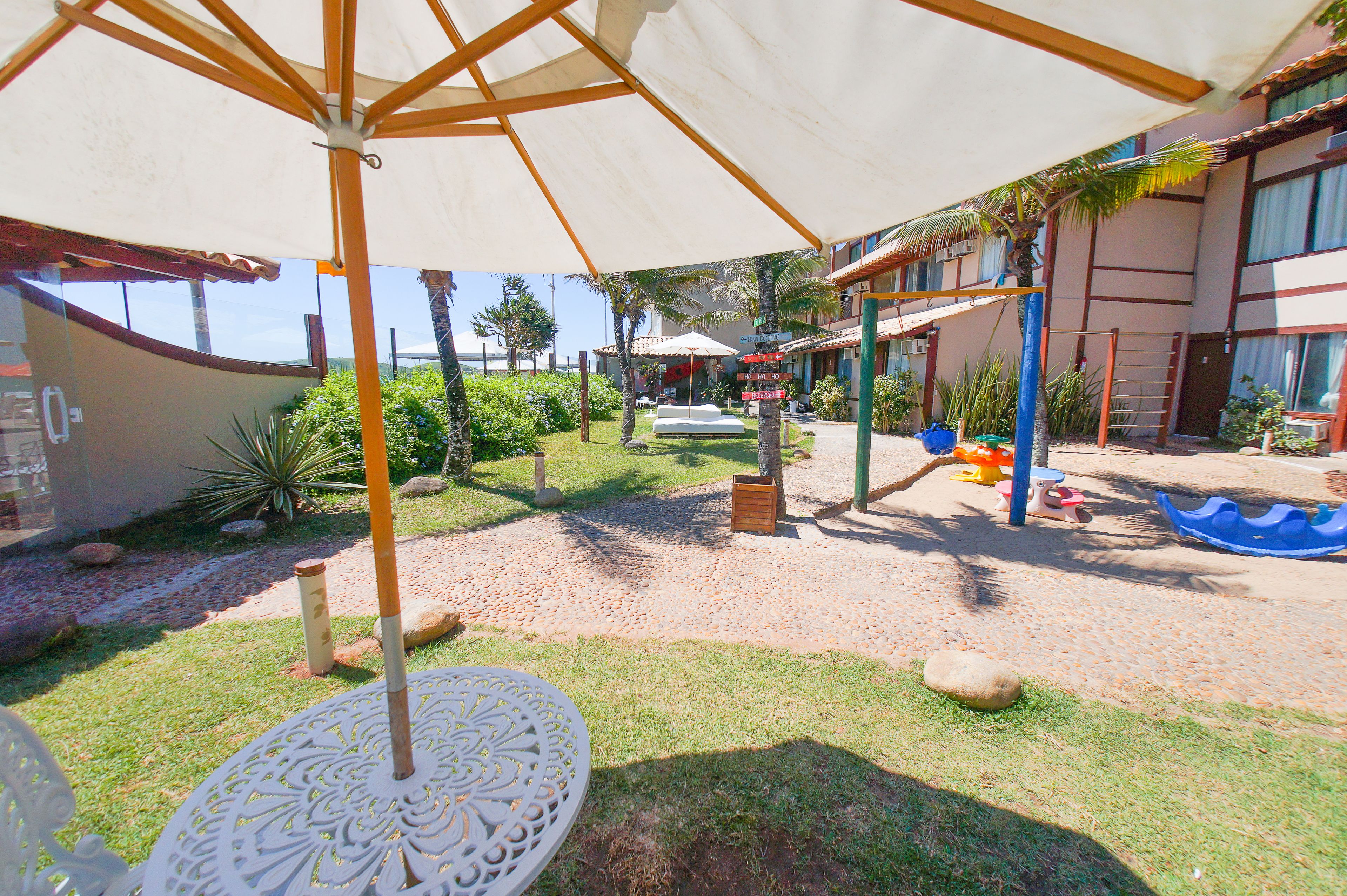 A covered outdoor area with a sandy ground, a white umbrella, and a small table.