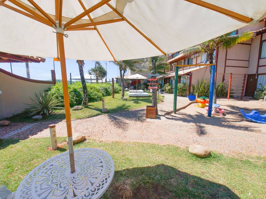 A covered outdoor area with a sandy ground, a white umbrella, and a small table.