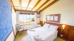 Una habitación de hotel con una cama, una silla, un ventanal con vistas y un cuadro en la pared.