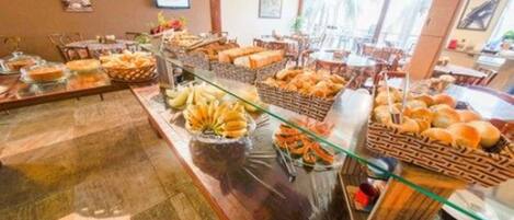 A buffet setup with various food items like bread, pastries, and fruits.