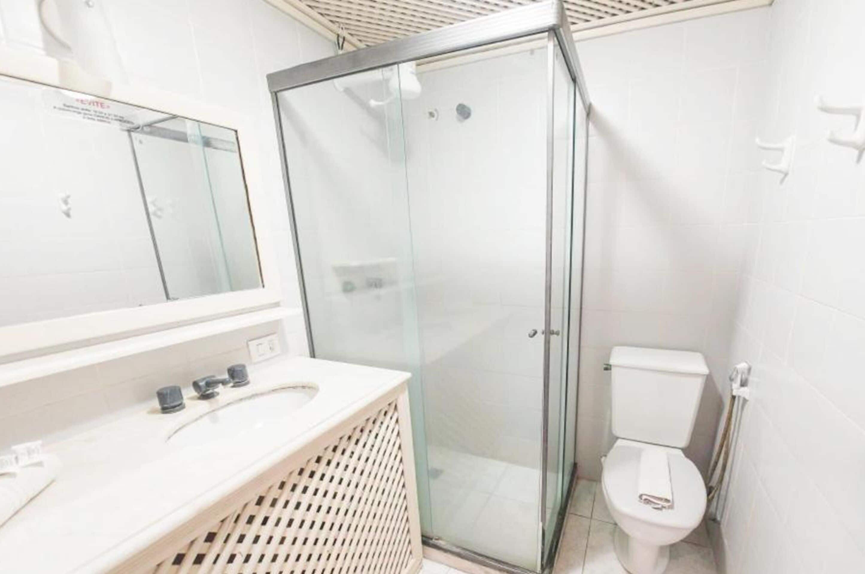 Un bagno moderno con cabina doccia in vetro, un water bianco e un mobile lavabo con specchio.