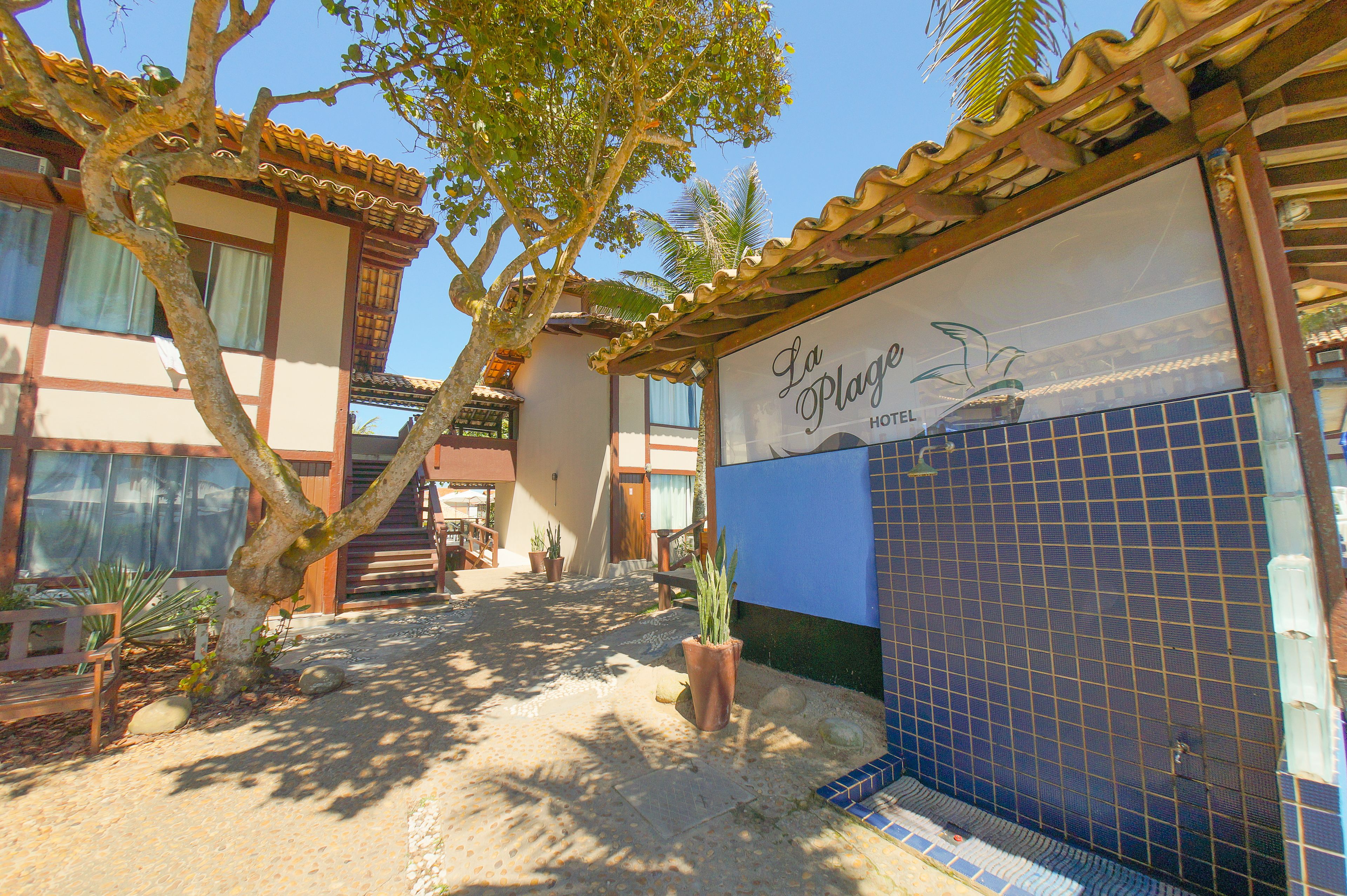 A hotel entrance with a tiled wall, a sign reading "La Plage Hotel", and a staircase leading to the entrance.
