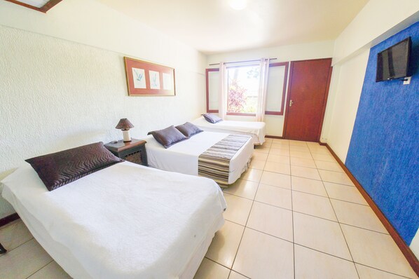 Habitación de hotel con dos camas, un televisor en la pared y una ventana con cortinas.