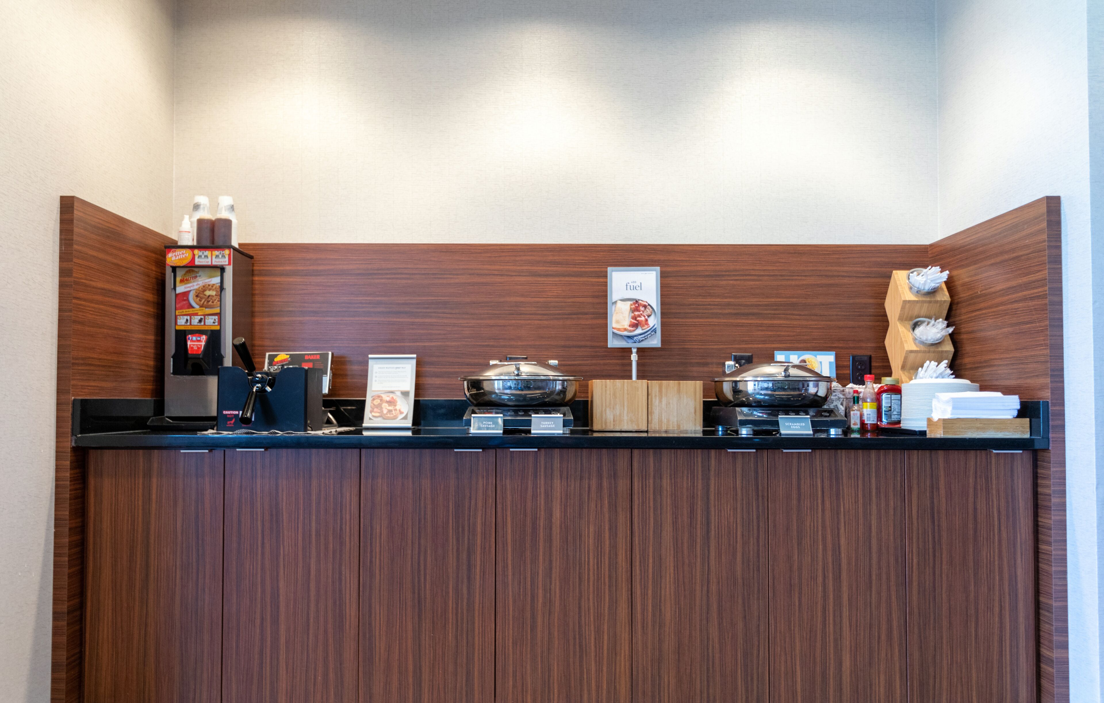 Un espace de petit-déjeuner en libre-service comprenant une machine à café, un présentoir de nourriture et un four à micro-ondes.