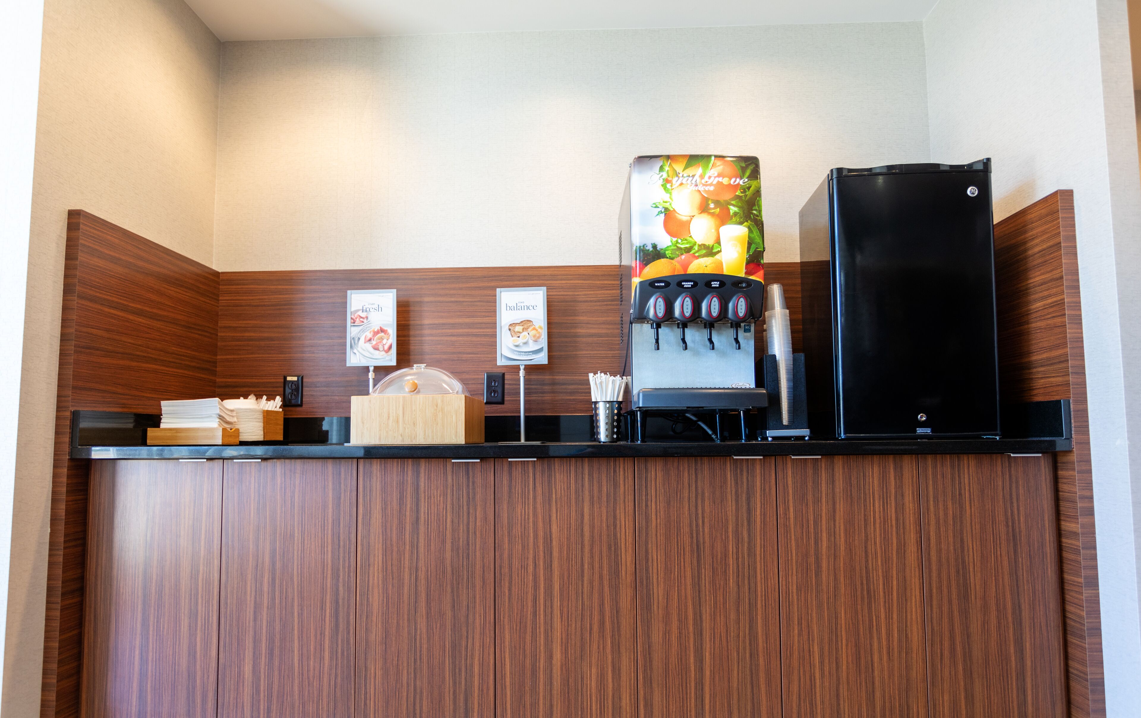 A coffee station with a coffee machine, a refrigerator, and a menu board.