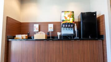 A coffee station with a coffee machine, a refrigerator, and a menu board.