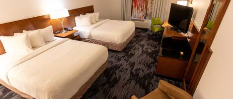 A hotel room with two beds, a desk with a computer, a chair, and a large window with curtains.