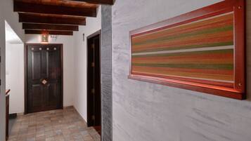 A hallway with a wooden door, a stone wall, and a colorful striped artwork.