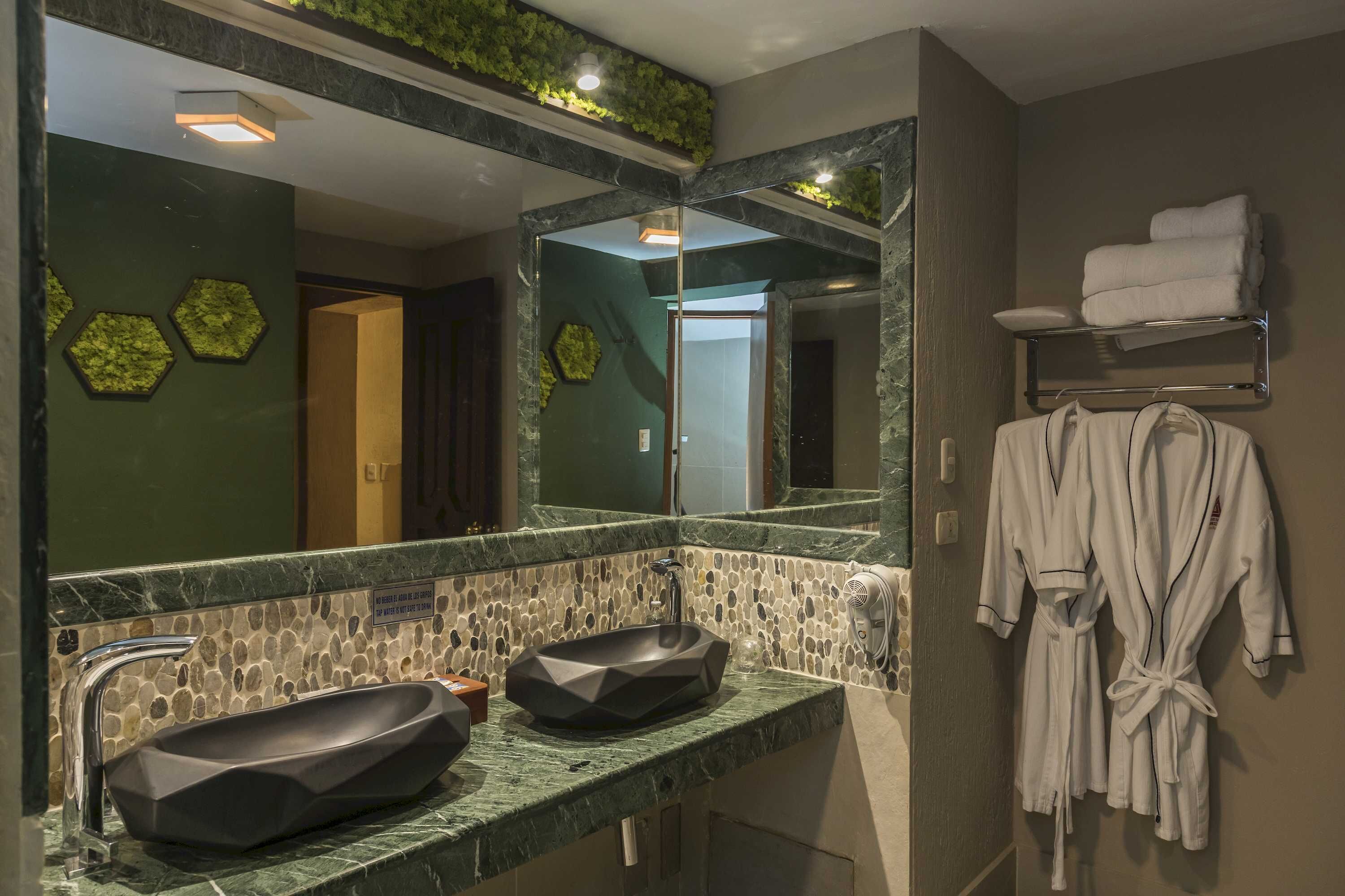 A modern bathroom with a large mirror, two sinks, and a towel rack.