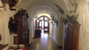 A corridor with arched ceilings, mounted animal heads, and a table with plates.