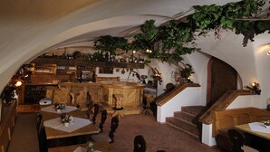 A rustic interior with wooden furniture, a bar area, and a staircase.
