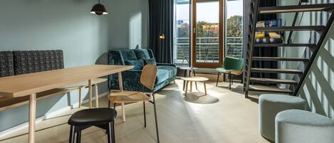 Ein modernes Wohnzimmer mit einem Holzesstisch, einer Couch und einer Treppe, die zu einem Balkon im Freien führt.