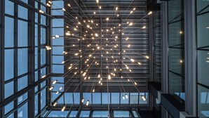 A modern building interior with a grid of windows and a ceiling with hanging light fixtures.