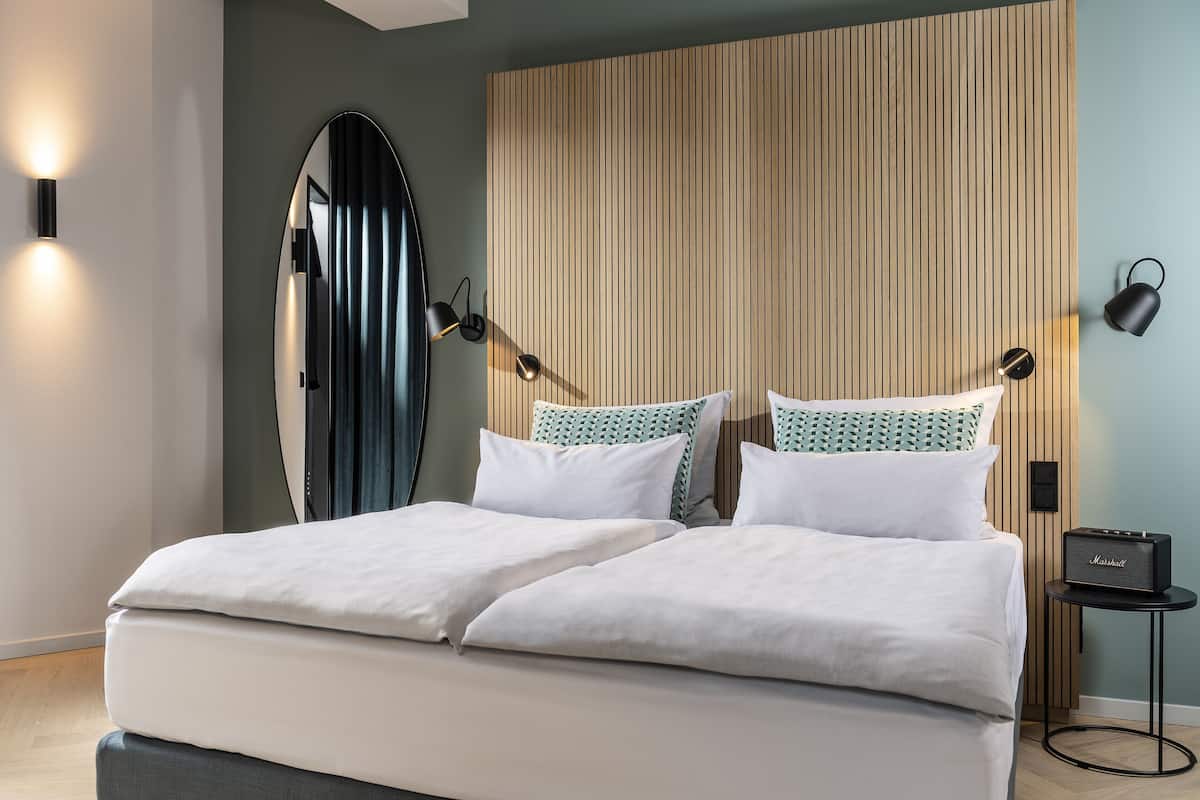 Un dormitorio moderno con una cama grande, un cabecero de listones de madera y dos lámparas de noche.