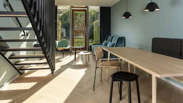 A modern interior with a wooden dining table, black chairs, a blue sofa, and a staircase with black railings.