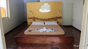 Een hotelkamer met een bed, een houten hoofdeinde en een geel accentmuur.