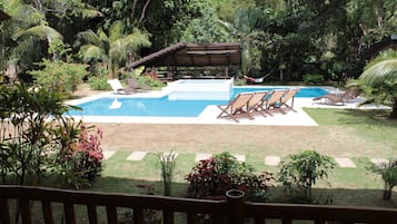 A backyard with a swimming pool, lounge chairs, and a pergola.