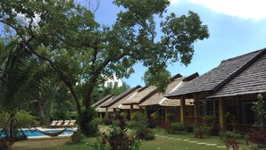 Een resort met meerdere bungalowgebouwen, een zwembad en weelderige begroeiing.