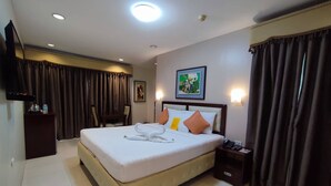 Habitación de hotel con una cama grande, una mesita de noche, un escritorio, una silla, un televisor de pantalla plana y un cuadro en la pared.