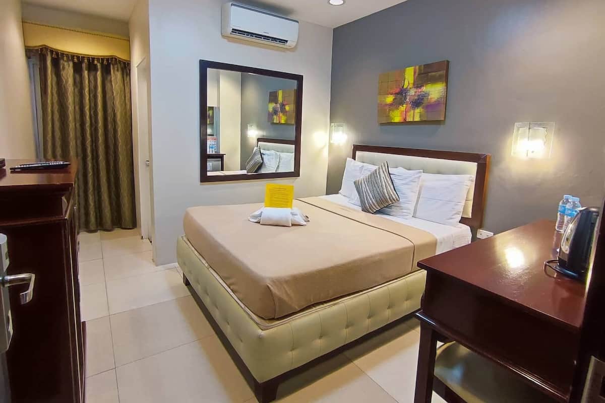 A hotel room with a bed, bedside table, and a desk.