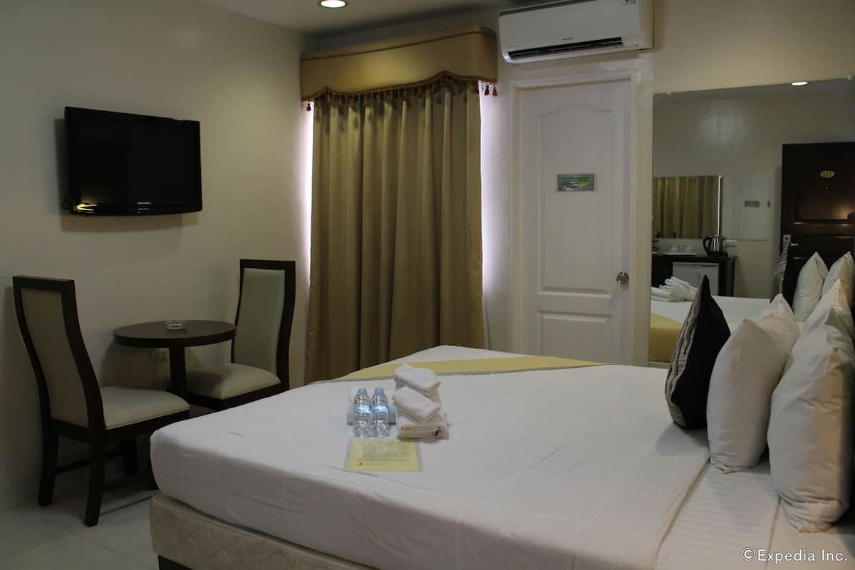 A hotel room with a bed, a TV, a desk, and a chair.