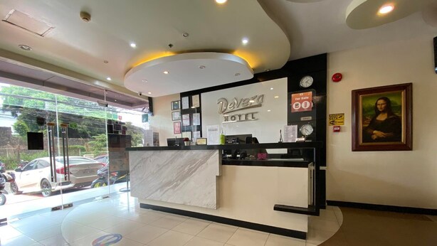 Zona de recepción de un hotel con mostrador de mármol, un reloj y una obra de arte enmarcada en la pared.
