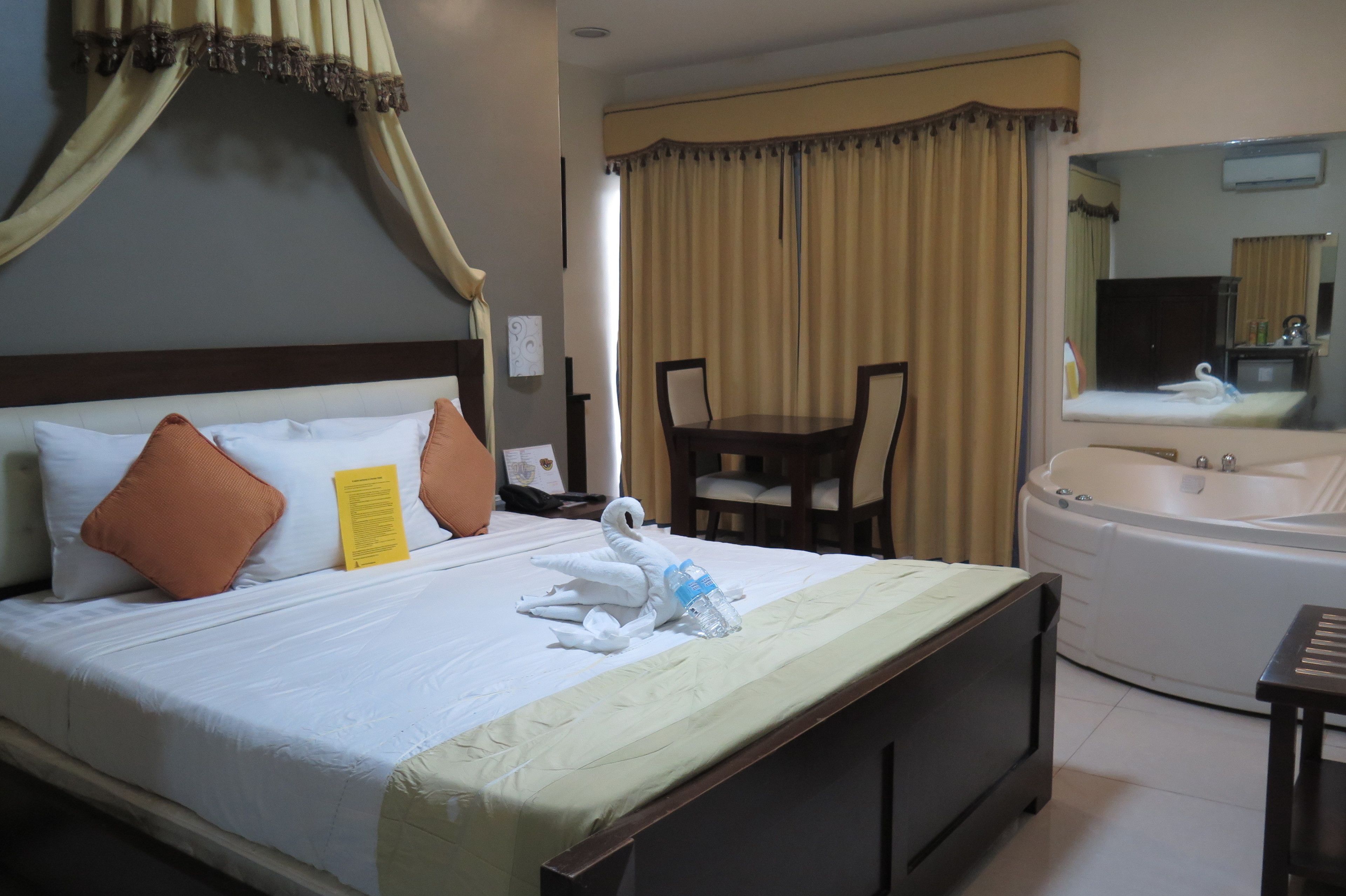 Une chambre d’hôtel avec un lit, une baignoire, une table à manger et une chaise.