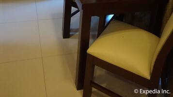 A compact kitchen with a microwave, a wooden cabinet, and a dining table with a chair.