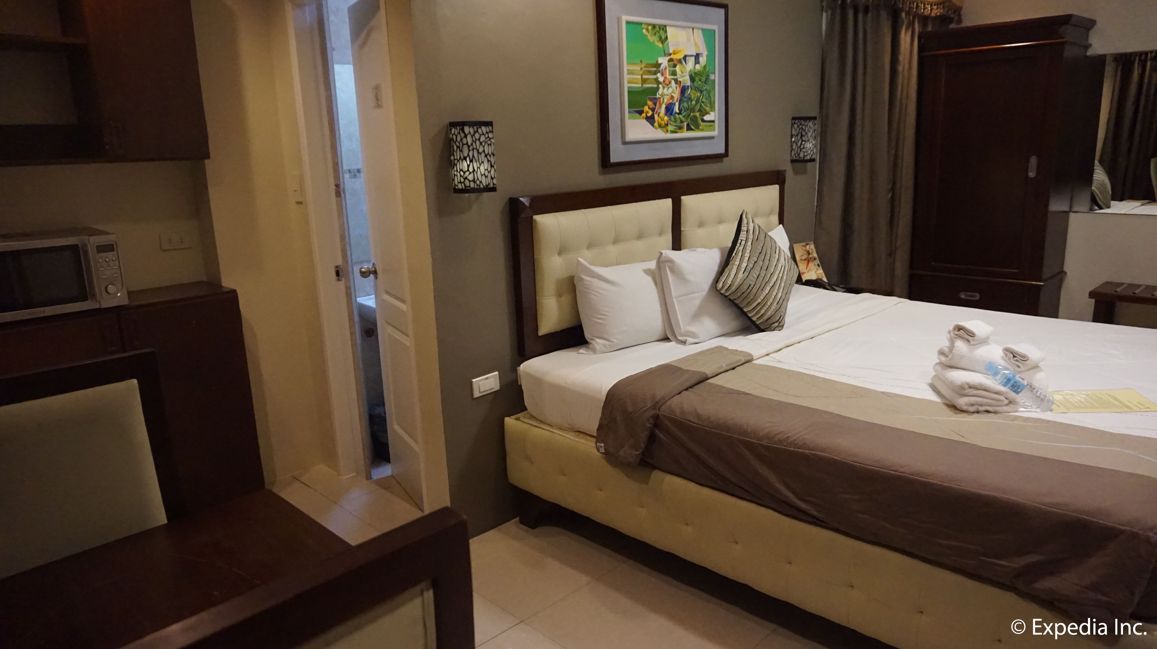 A hotel room with a bed, a desk, and a microwave.