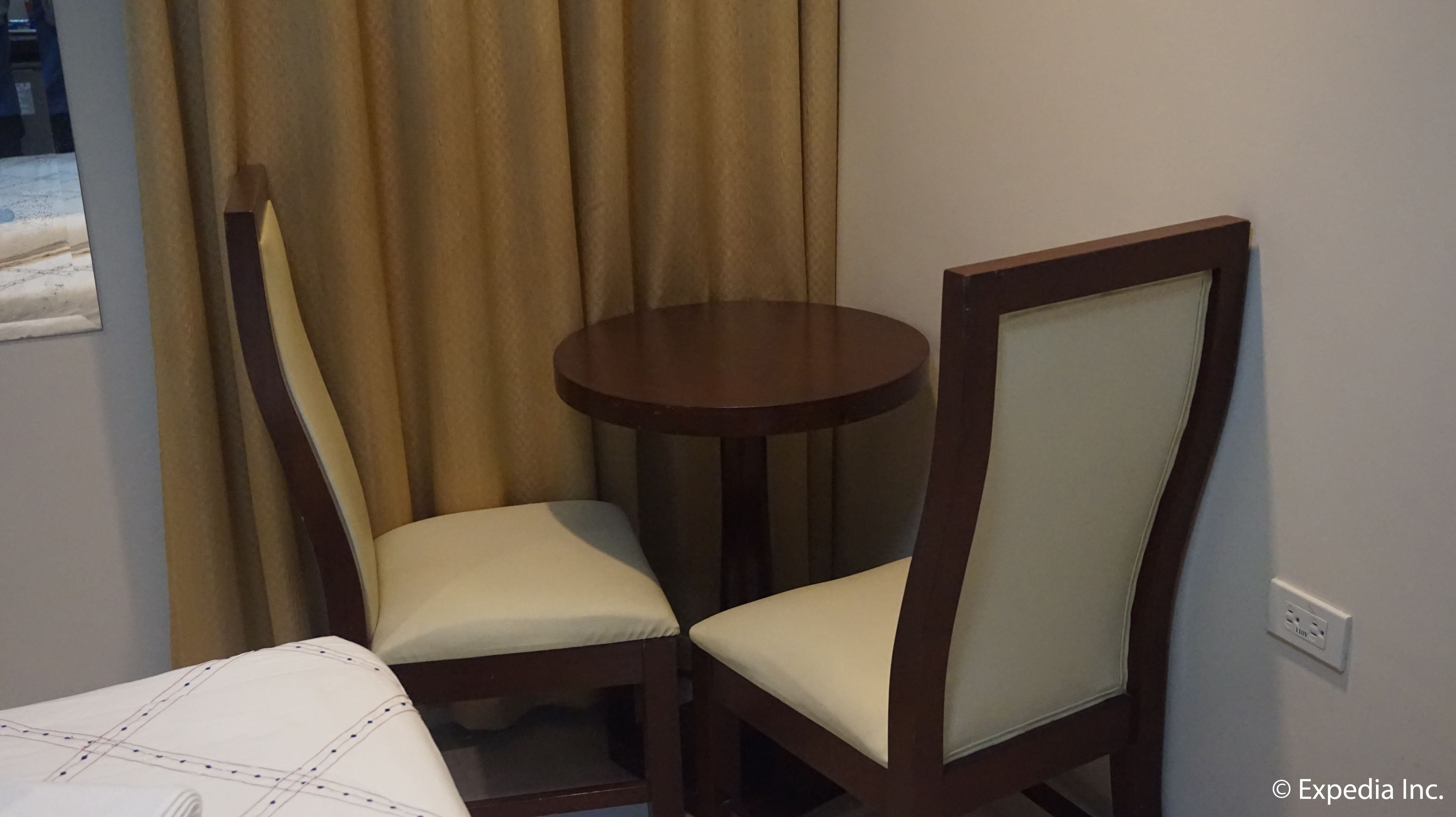 A small room with a bed, a round table, and two chairs.