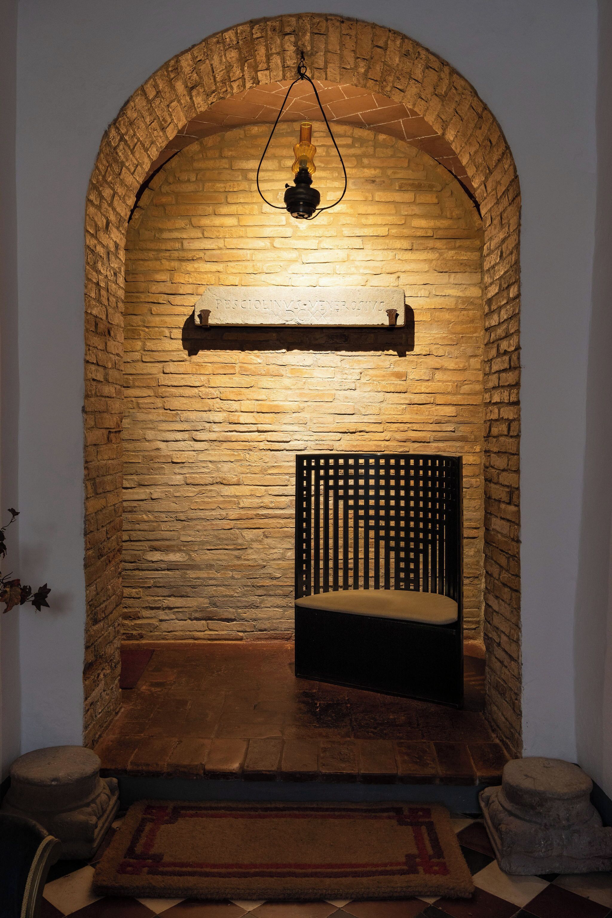 A room with a brick wall, a bench, a hanging light fixture, and a shelf.